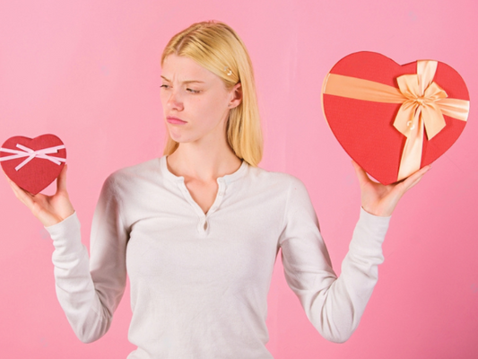 Does size really matter. Woman hold big and little heart shaped gift boxes. Which one she prefer. 