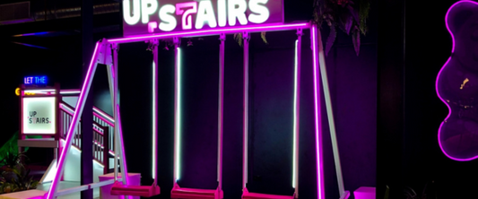Swings with purple neon lights at entrance to Swingers Club
