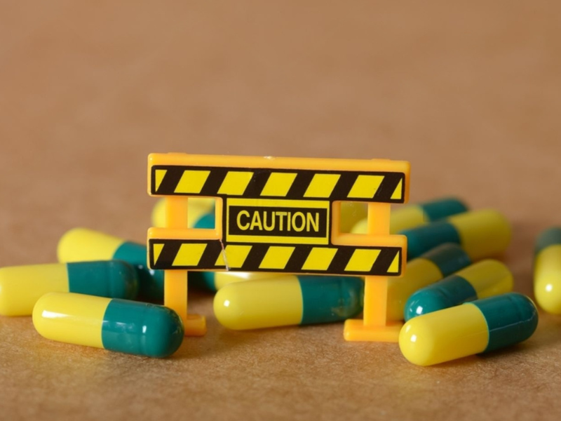 Toy construction barrier with 'CAUTION' sign surrounded by yellow and green capsules on a brown background