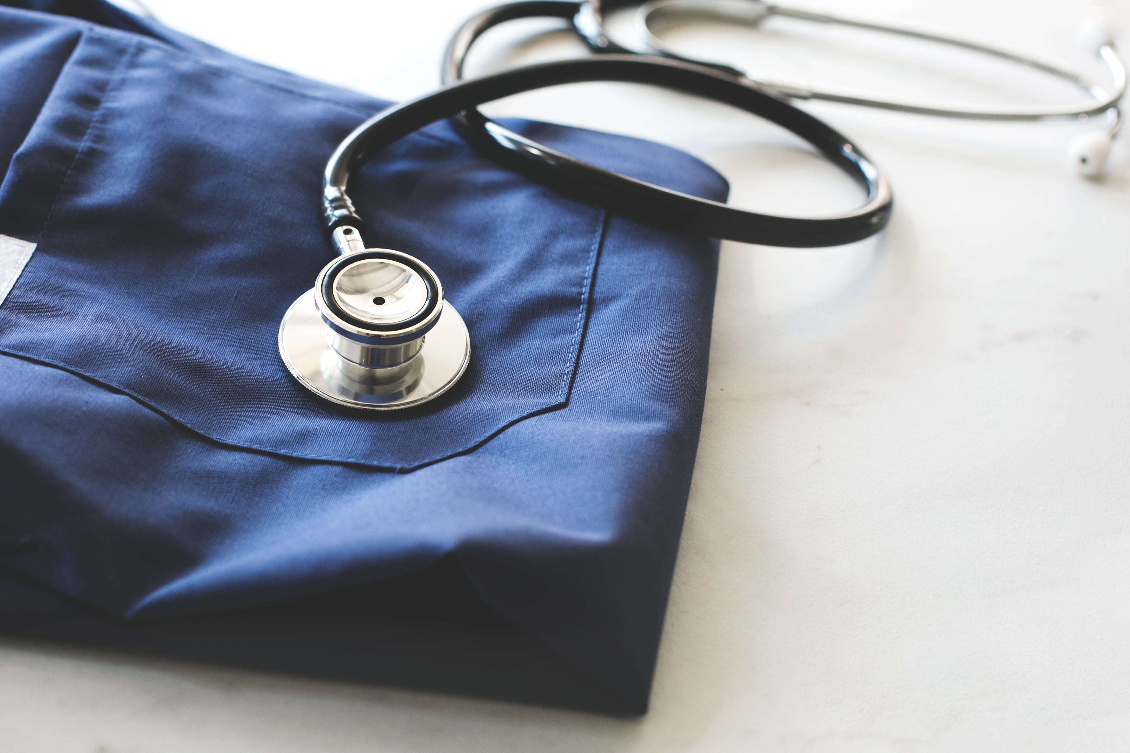 Stethoscope and folded blue medical uniform